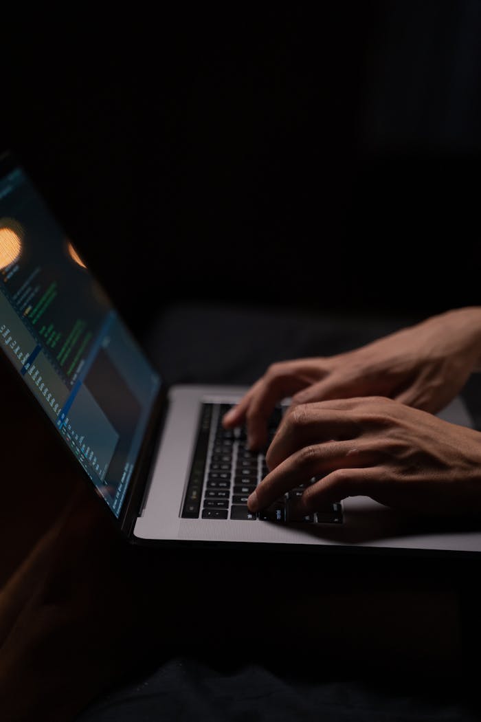 mobile-01 Hands typing code on a laptop keyboard in a dark room, capturing the essence of late-night programming.